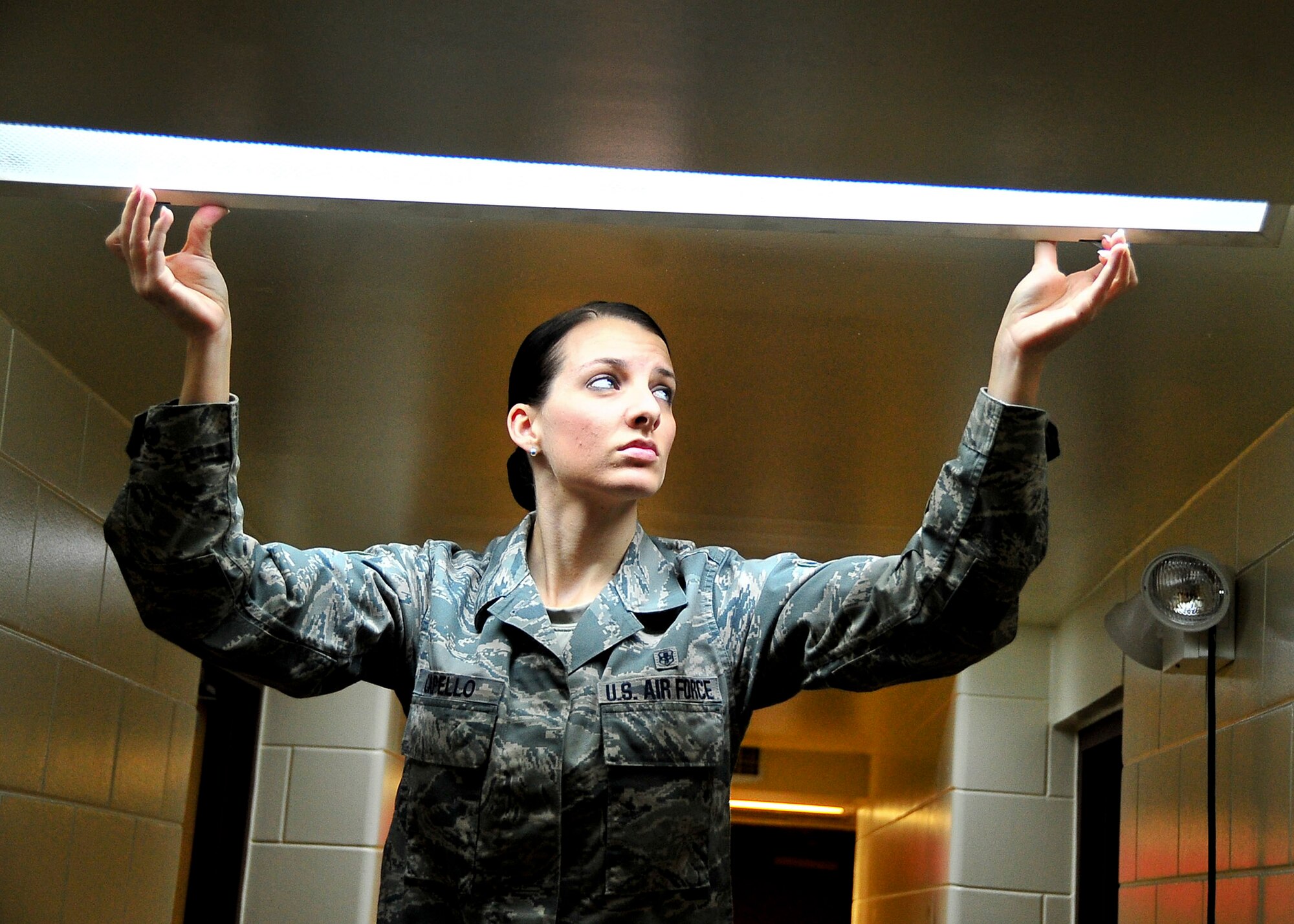 Staff Sgt. Amber Capello, 51st Civil Engineer Squadron Airman dorm leader, changes out a light fixture in a hallway here, Feb. 29, 2012.  Capello is responsible for dormitories which house 192 residents. (U.S. Air Force photo/Senior Airman Adam Grant)