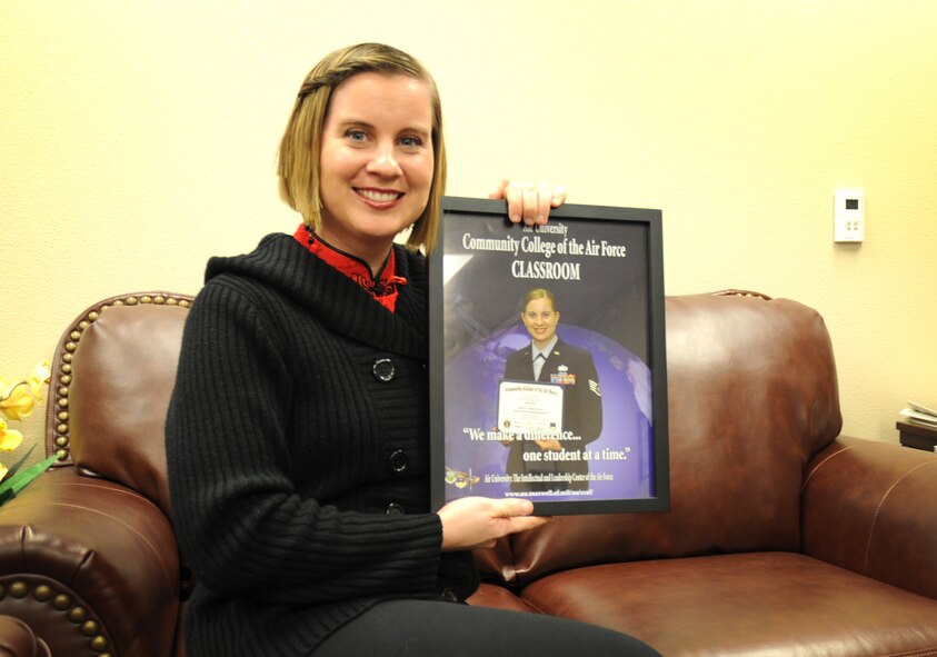 U.S. Air Force Tech. Sgt. Melinda Morris, 27th Special Operations Wing Equal Opportunity, proudly holds up a framed image of herself on the Community College of the Air Force marketing poster in her office at Cannon Air Force Base, N.M., Feb. 15, 2012. Women?s History Month is held throughout March and recognizes the contributions and achievements of all women to the American culture in order to increase awareness, mutual respect and understating. (U.S. Air Force photo by Airman 1st Class Alexxis Pons Abascal)  