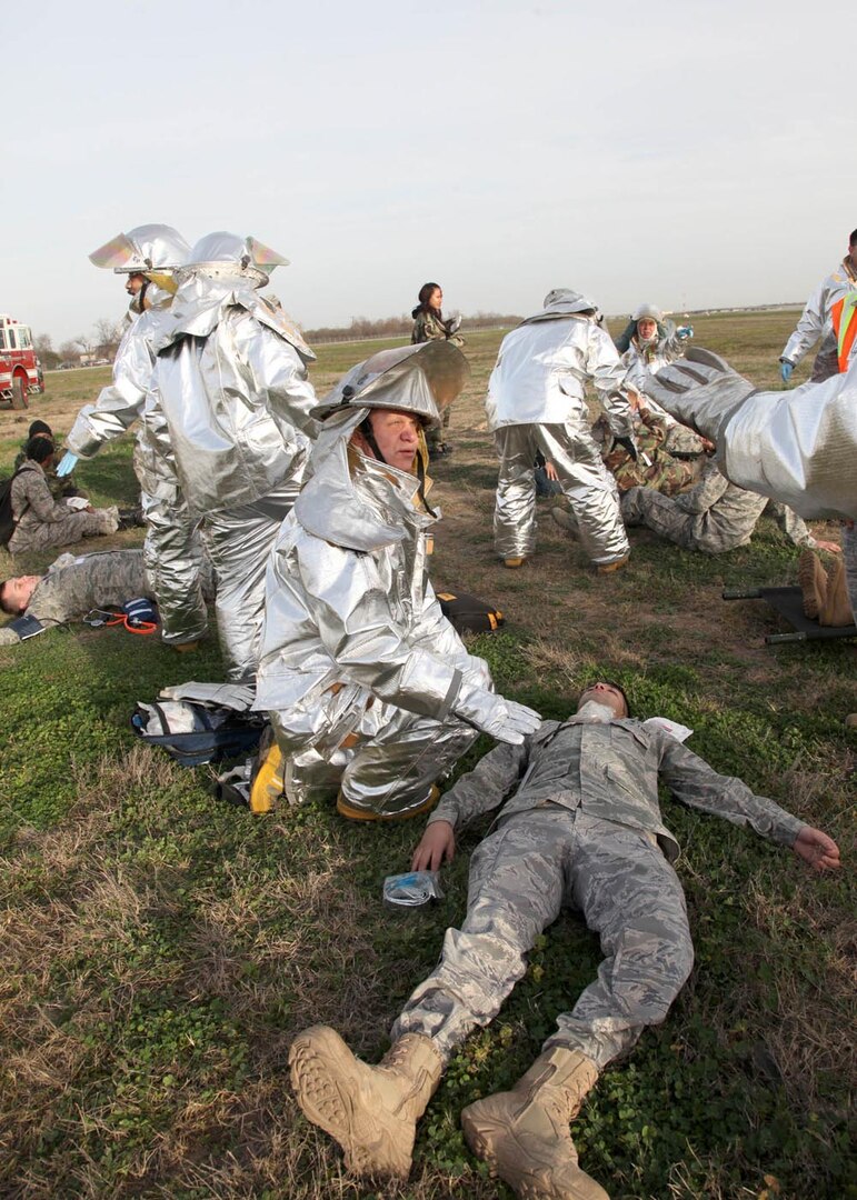 Lead firefighter Jeffery Newman, 802nd Civil Engineer Squadron, aids Senior Airman Ismael Perez, 59th Medical Wing, who is playing the role of an injured pilot during a recent Major Accident Response Exercise at Joint Base San Antonio-Lackland. Events like the MARE, which simulated the crash of an aircraft, test the response capabilities of emergency management and support organizations on base. Similar exercises prepare Air Force organizations for real-world emergencies, and for evaluations like the weeklong Air Education and Training Command Compliance Inspection, which begins Monday. (U.S. Air Force photo/Robbin Cresswell)
