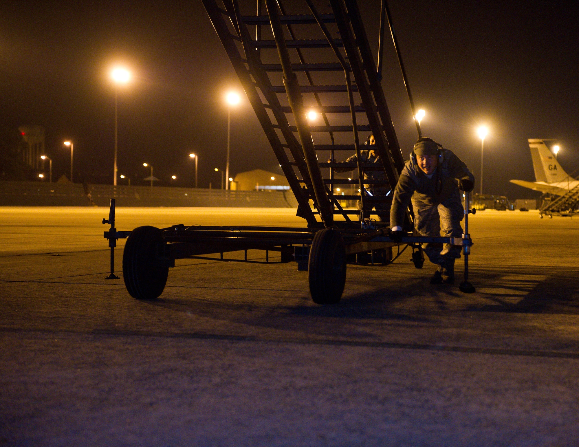 Crew chiefs from the 116th and 461st Air Control Wings push a B-7 maintenance stand to the door of an E-8 Joint STARS returning from a night mission at Robins Air Force Base, Ga., Feb. 15, 2012. The stand, normally used for performing maintenance on the aircraft, is also utilized as a set of stairs for the aircrew to exit the aircraft.   (National Guard photo by Master Sgt. Roger Parsons/Released)