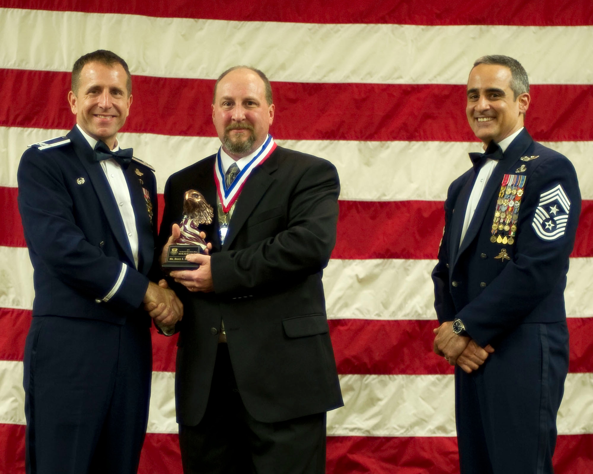 Col. Jim Slife, commander of the 1st Special Operations Wing, left, and Chief Master Sgt. Ramon Colon-Lopez, command chief of the 1st SOW, right, present Bruce Sheffield, 1st Special Operations Support Squadron, center, with the 1st Special Operations Wing Wage Grade Civilian of the Year award at the 2011 Team Hurlburt Annual Awards Banquet at the Soundside Club at Hurlburt Field, Fla., Feb. 24, 2012. (U.S. Air Force photo by Airman 1st Class Gustavo Castillo) (Released) 