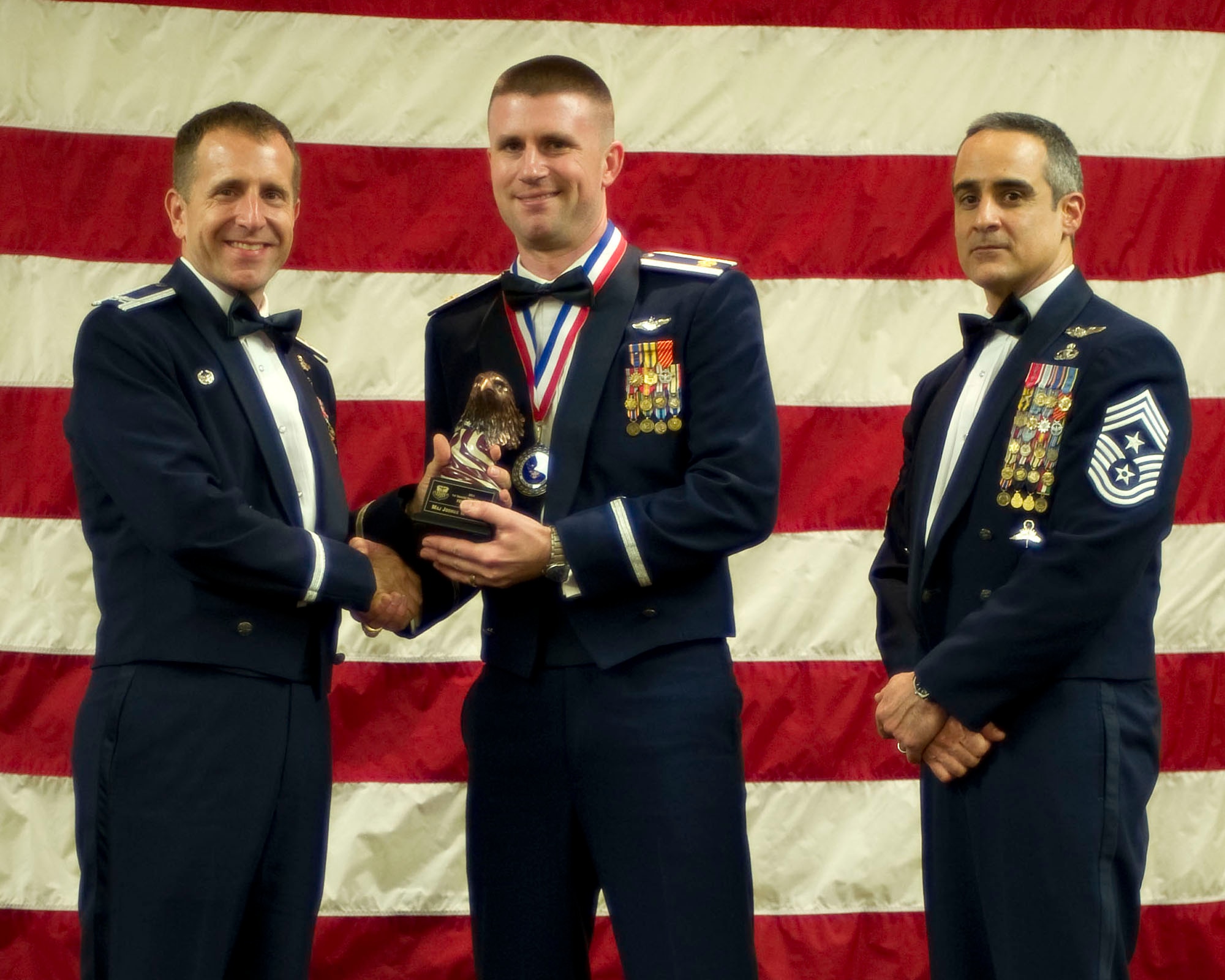 Col. Jim Slife, commander of the 1st Special Operations Wing, left, and Chief Master Sgt. Ramon Colon-Lopez, command chief of the 1st SOW, right, present Maj. Joshua Petry, 15th Special Operations Squadron, center, with the 1st SOW Field Grade Officer of the Year award at the 2011 Team Hurlburt Annual Awards Banquet at the Soundside Club at Hurlburt Field, Fla., Feb. 24, 2012. (U.S. Air Force photo by Airman 1st Class Gustavo Castillo) (Released) 