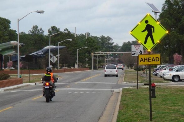 Recently installed pedestrian crossing signs in front of the Seymour Johnson Support Center on Wright Brothers Ave. are using solar-powered light-emitting diode caution lights to improve crosswalk safety. These signs are part of a base-wide energy saving initiative. (Courtesy photo) 