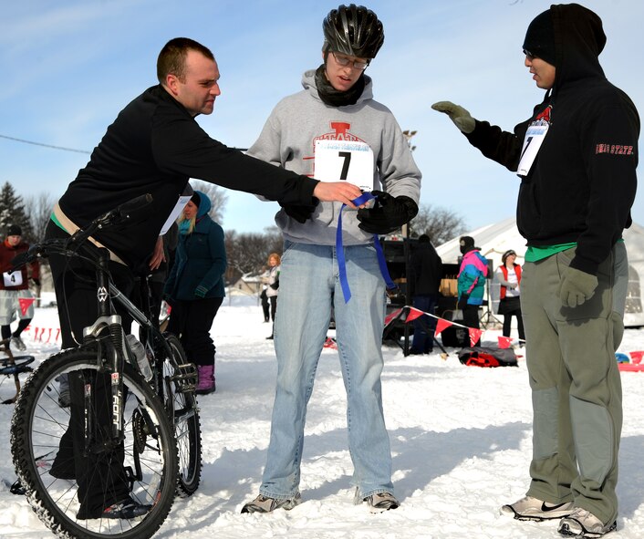 Airmen 1st Class Jeffrey Lowder, left, and Marco Cervantes help fellow A1C Alex Shiverick get ready to start the seven-mile long bicycle race as part of the 3rd Annual Cold Avenger’s End It Extreme North Dakota Iceman Triathlon on Feb. 25, 2012, in downtown Grand Forks, N.D.  (U.S. Air Force photo Airman 1st Class Xavier Navarro)