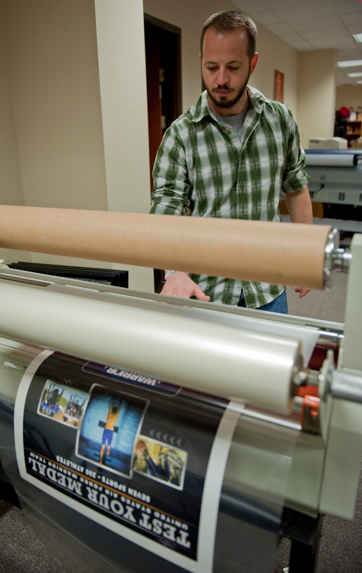 JT McKeen, 39th Force Support Squadron marketing graphic artist, laminates a poster Feb. 29, 2012, at Incirlik Air Base, Turkey. The marketing office creates and prints posters, pamphlets, and other showcase items for the Incirlik community. Marketing also runs the 39th FSS website, blog and Facebook page, sells advertising, and promotes base events. (U.S. Air Force photo by Senior Airman Anthony Sanchelli/Released)