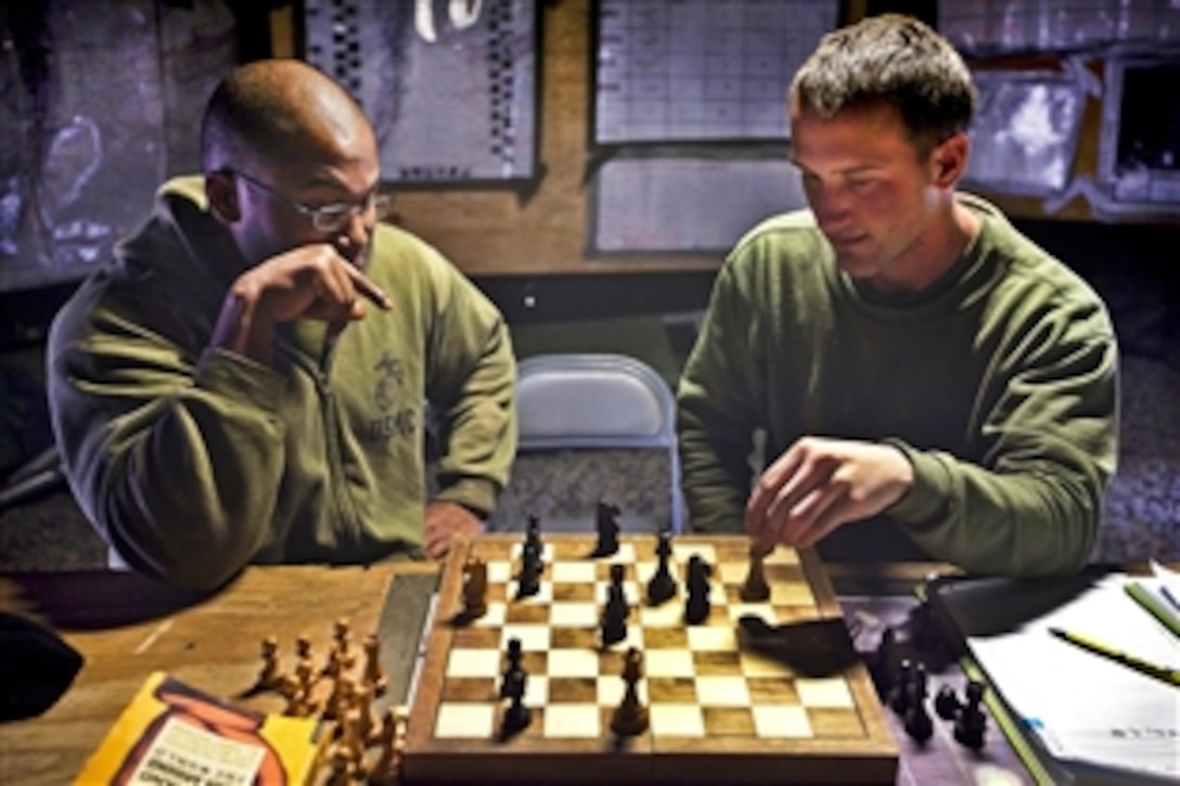 U.S. Marine Corps Sgt. Jeremy Scott, left, and Lance Cpl. Tyler Dickinson play chess after work on Patrol Base Bury in the Garmsir district of Afghanistan's Helmand province, Feb. 26, 2012. Scott and Dickinson are assigned to Kilo Company, 3rd Battalion, 3rd Marine Regiment. Concertina wire and giant Hesco barriers surround the base, which is Kilo Company's home during its seven-month deployment to the province.