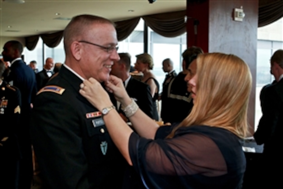 Army Chief Warrant Officer 5 Kevin Purtee, who received a Distinguished Flying Cross for evacuating a wounded soldier during the Battle of Donkey Island in Iraq, talks to his wife, Michele Tumino, as she straightens his bow tie at a reception to honor Iraq War veterans in Crystan City, Va., Feb. 29, 2012.