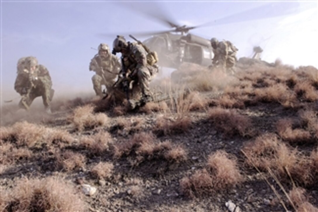 U.S. Special Operations personnel take cover to avoid flying debris as they prepare to board a UH-60 Black Hawk helicopter during a mission in Kunar province, Afghanistan, on Feb. 25, 2012.  The soldiers are conducting reconnaissance for a future village stability platform, a site Afghan forces and coalition Special Operations Forces will use to live and work with villagers.  