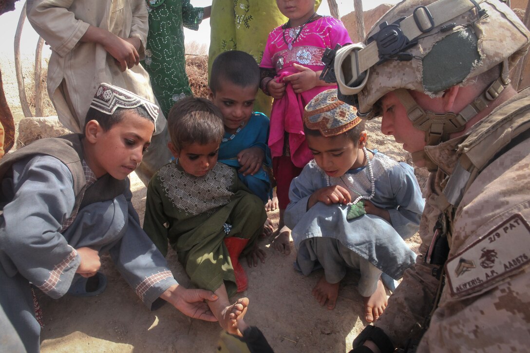 U.S. Marine Cpl. Austin Aliferis, a fire team leader with the Regimental Combat Team 5 Police Advisor Team working in support of 2nd Battalion, 9th Marine Regiment, applies a bandage to an Afghan child's foot during a clearing operation here March 1, 2012. Aliferis and his team passed out food, water and candy to the group of children before moving to support Afghan police clearing the area of suspected insurgent activity. In addition to advising Afghan forces in the blocks of Marjah, 2nd Bn., 9th Marines conducted partnered counternarcotics missions with the Afghan National Interdiction Unit in the Bari Desert during Operation Psarlay Taba. The partnered force captured around 26,000 pounds of assorted opium products over the course of the four-month operation. Lance Cpl. Tyler Reiriz