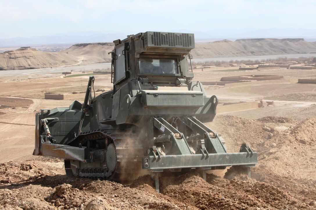 Cpl. Robert Beich, a heavy equipment operator with Engineer Support Company, 9th Engineer Support Battalion, 1st Marine Logistics Group (Forward) works on leveling a hill during a road improvement mission in Helmand province, Afghanistan, Feb. 15. The terrain in the local area makes road improvement missions challenging.::r::::n::::r::::n::::r::::n::