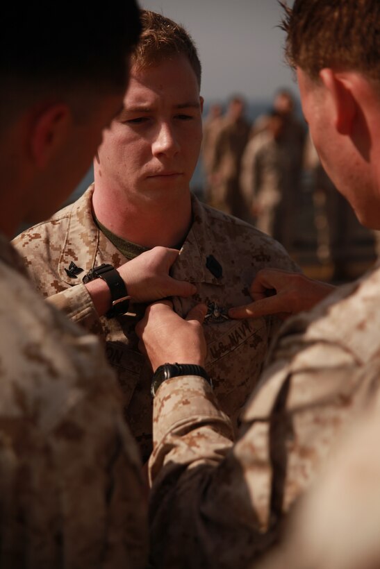 Marines present a Navy Fleet Marine Force pin to Petty Officer 3rd Class Fletcher Carson aboard USS Makin Island here March 1. The Marines and sailor serve with Battalion Landing Team 3/1, the ground combat element for the 11th Marine Expeditionary Unit. The unit is deployed as part of the Makin Island Amphibious Ready Group, a U.S. Central Command theater reserve force. The group is providing support for maritime security operations and theater security cooperation efforts in the U.S. Navy's 5th Fleet area of responsibility.