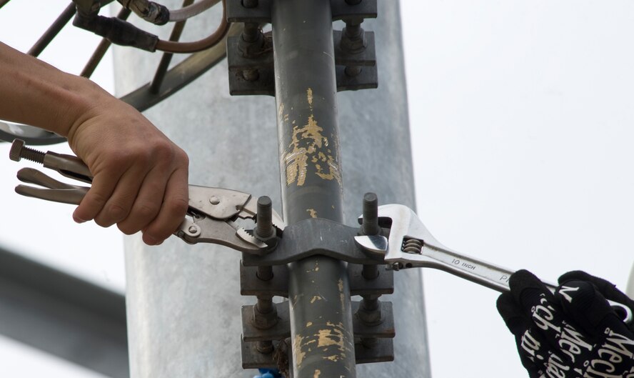 Airmen from 2nd Communications Squadron cable and antenna maintenance fasten an Aircraft Alerting Communications Electromagnetic pulse antenna onto the tower in front of the 2nd Civil Engineer Squadron building on Barksdale Air Force Base, La., Feb. 28. The Airmen hooked up the AACE antenna to temporarily replace the antenna at the top of the tower while it is being repaired. (U.S. Air Force photo/Airman 1st Class Benjamin Gonsier)(RELEASED)