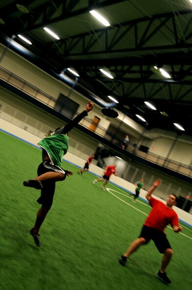 Airman 1st Class Luis Sepulveda, 319th Medical Group, jumps to make a catch as Senior Airman Adam Powers, 319th Civil Engineer Squadron, watches during the Grand Forks Air Force Base, N.D., Ultimate Frisbee Championship game on March 1, 2012. The 319th Civil Engineer Squadron came out on top with their 5th consecutive championship game win. (U.S. Air Force photo by Staff Sgt. Amanda N. Grabiec)