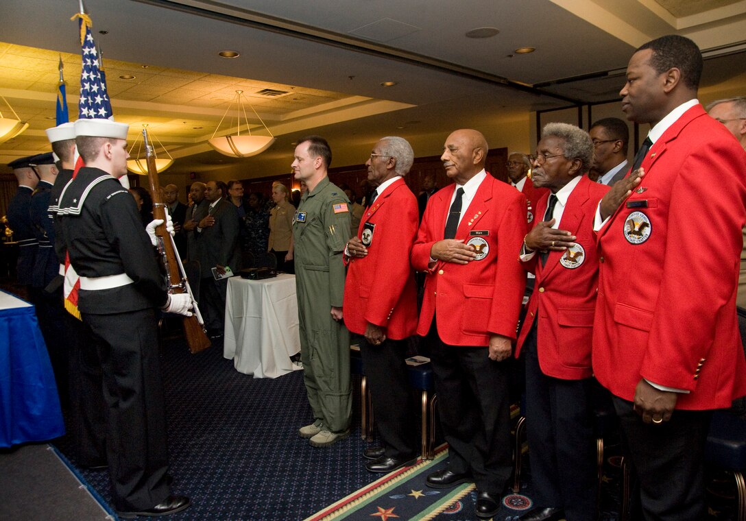 Colonel Ken Rizer, 11th Wing/Joint Base Andrews commander, and a group of Tuskegee Airmen pay homage as a Joint Service Honor Guard presents the Colors in the Annapolis room of the Club at Andrews Feb. 28. The Tuskegee Airmen gave individual accounts of their  lives as the first African-American pilots in the Army Air Corps and later open the floor for a panel discussion. (Photo/Bobby Jones)