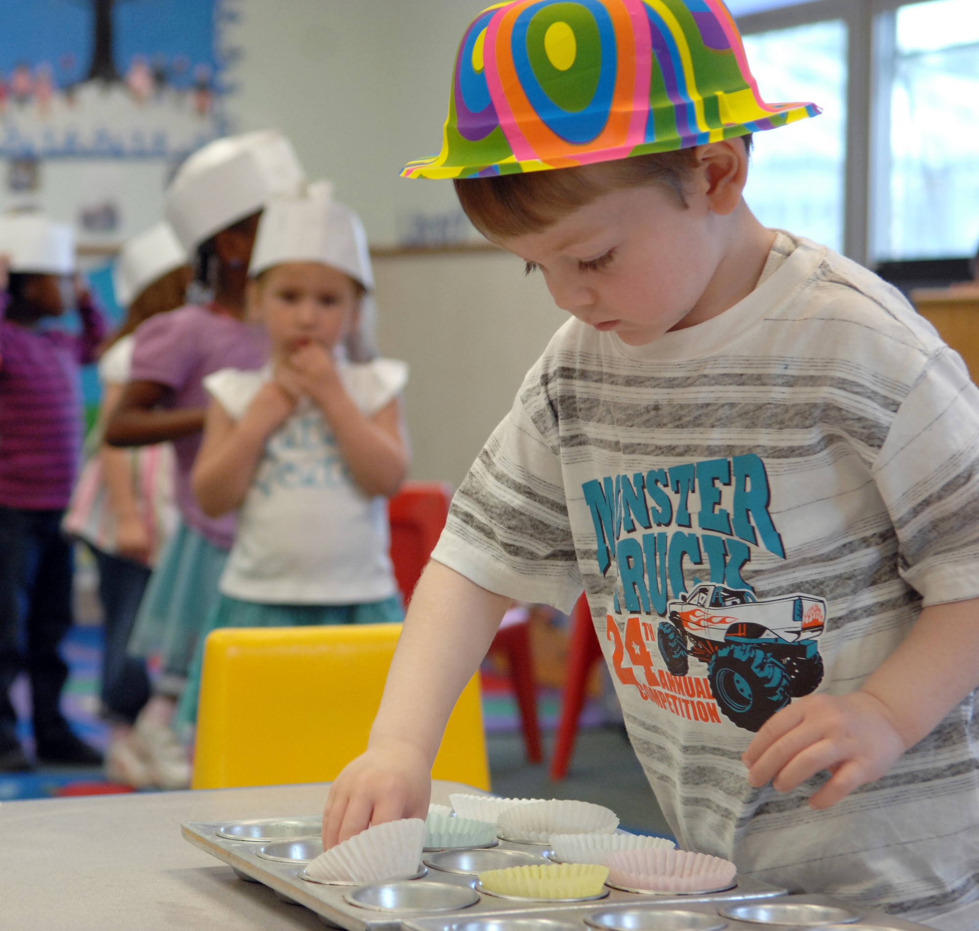 Caleb Gunter, 4, son of Staff Sgt. Sean Gunter, 2nd Munitions Squadron, places baking cups into a cupcake tray at the Child Development Center on Barksdale Air Force Base, La., Feb. 29. Gunter celebrated his 4th birthday with his classmates by making cupcakes. Teachers  supervised the children with mixing, pouring, and baking of the cupcake batter. (U.S. Air Force photo/Airman 1st Class Joseph A. Pagán Jr.)(RELEASED)