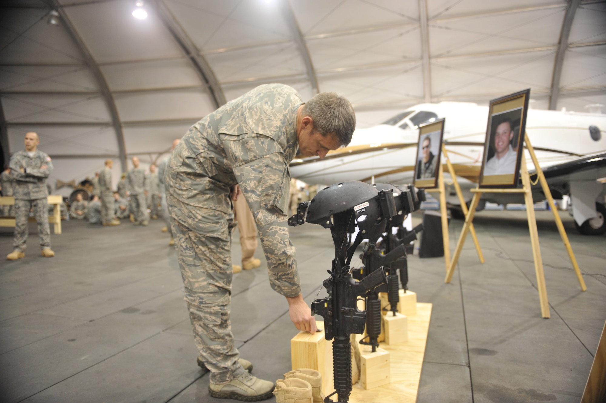 Lt. Col. Justin Hoffman, commander of the 34th Special Operations Squadron, rests a squadron coin on a display case honoring the memory of 1st Lt. Justin Wilkens, 34th SOS, during a memorial service at Camp Lemonnier, Djibouti, Feb. 19, 2012. Wilkens along with Capt. Ryan P. Hall from the 319th Special Operations Squadron, Capt. Nicholas S. Whitlock from the 34th Special Operations Squadron and Senior Airman Julian S. Scholten from the 25th Intelligence Squadron all died in a Feb. 18, 2012, U-28A crash in Djibouti, Africa. (U.S. Air Force photo/Staff Sgt. Stephen Linch)