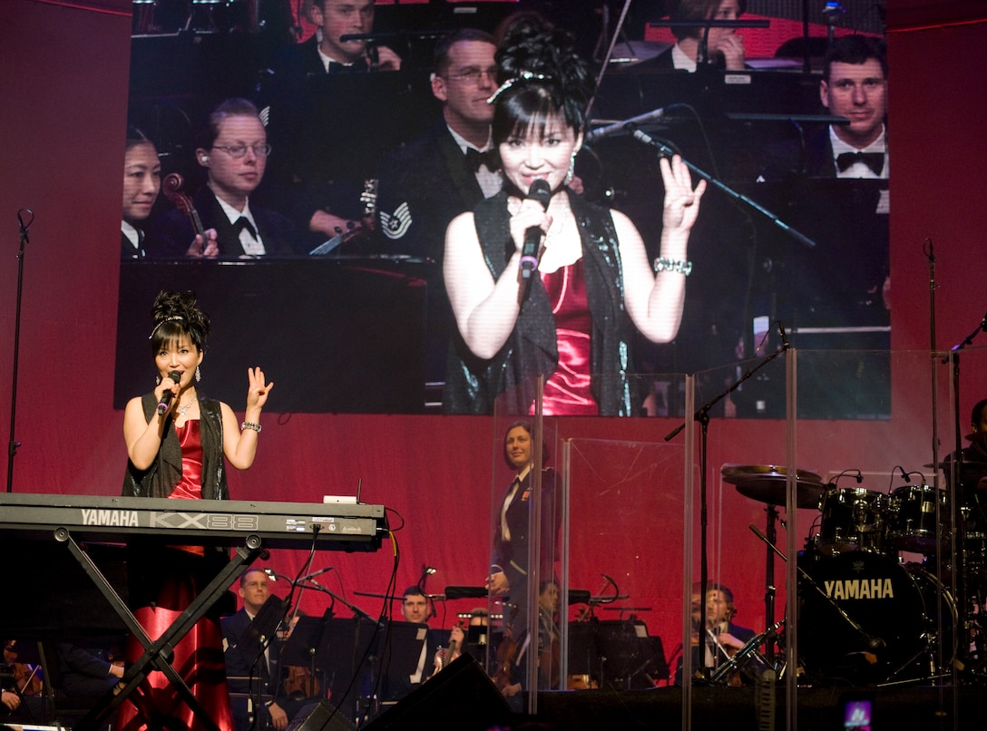 Keiko Matsui, jazz pianist, lauds the accompaniment of 2nd Lt. Shanti Noland, United States Air Force Band conductor, center, and the USAF Band during the 47th Annual Guest Artist Series at Daughters of American Revolution Constitution Hall in Washington, D.C. on Feb. 26. It was the second time the USAF Band has played with the renowned jazz professional.   (Photo/Bobby Jones)