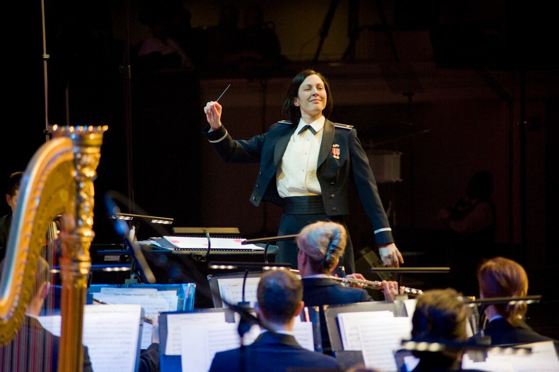 Second Lt. Shanti Nolan, United States Air Force Band conductor, guides USAF Band members through a song prior to Keiko Matsui, jazz pianist, takes center stage during the 47th Annual Guest Artist Series at Daughters of American Revolution Constitution Hall in Washington, D.C., on Feb. 26. (Photo/Bobby Jones)