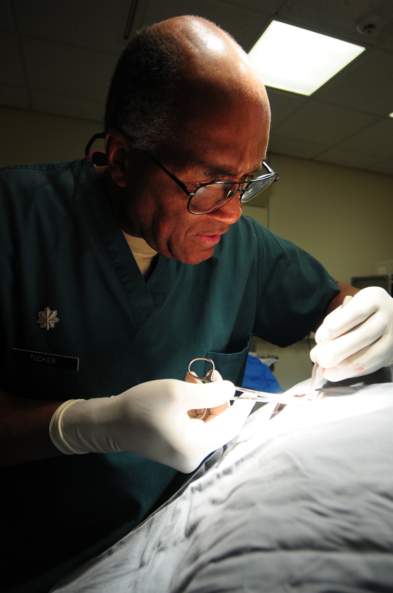 ROYAL AIR FORCE LAKENHEATH, England -- Lt. Col. (Dr.) Duane Tucker, 48th Medical Operations Squadron dermatologist, applies sutures on a patient after a conservative mole excision, Dec. 21, 2011. The 48th Medical Group recently won the Air Force Surgeon General's Best Hospital of the Year for the third year in a row. (U.S. Air Force photo by Senior Airman Lausanne Morgan)