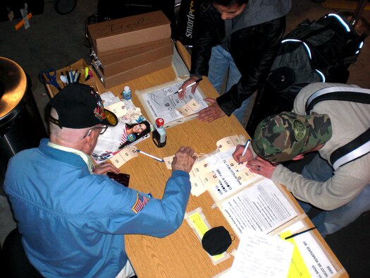 Retired U.S. Army 1st Sgt. Evert “Sarge” Carter helps service members check their bags into the Seattle-Tacoma International Airport USO baggage annex Feb. 8, 2012. Anyone who stops by the annex has the chance to hear a piece of history as Sarge recounts his stories from serving in World War II, the Korean War, the Vietnam War and the Cold War. (U.S. Air Force photo by Senior Airman Brigitte N. Brantley/Released)