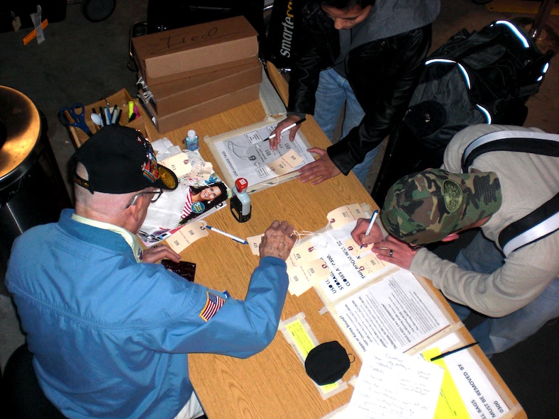 Retired U.S. Army 1st Sgt. Evert “Sarge” Carter helps service members check their bags into the Seattle-Tacoma International Airport USO baggage annex Feb. 8, 2012. Anyone who stops by the annex has the chance to hear a piece of history as Sarge recounts his stories from serving in World War II, the Korean War, the Vietnam War and the Cold War. (U.S. Air Force photo by Senior Airman Brigitte N. Brantley/Released)