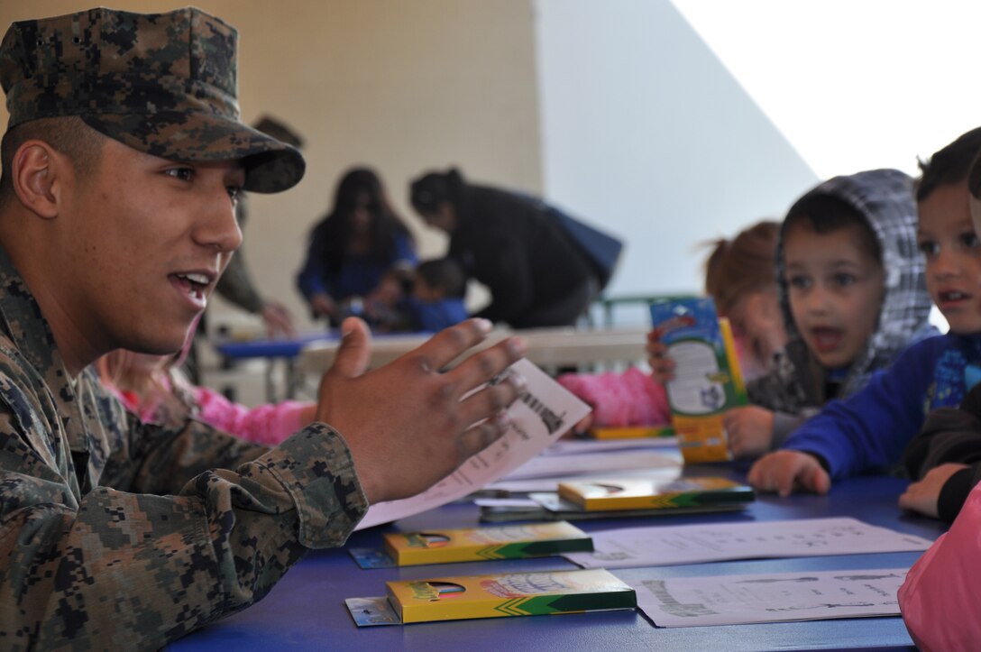 Private First Class Adrian Velasco, an administrative clerk with Headquarters Battalion, Marine Corps Logistics Base Barstow, explains to children of base's Child Development Center who Dr. Seuss was and entertains them by telling some of his rhymes while they color at McTureous Hall aboard base during the Dr. Seuss Birthday Bash March 2. For the event, children were taught about the importance of reading and learned new ways to have fun while doing it.
