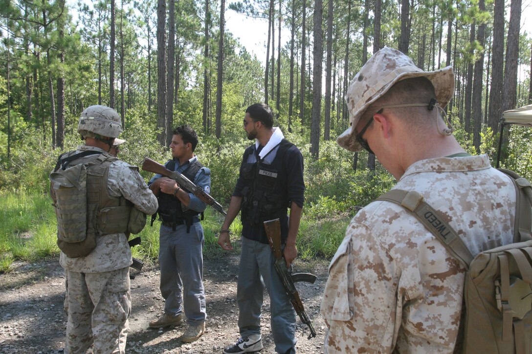 Lance Cpl. Randall Hernandez, squad leader for 2nd squad, 3rd platoon, 2nd Battalion, 6th Marine Regiment, 2nd Marine Division, talks with role players, during a training exercise. The role players act as Afghan National Police. During the exercise the Marines with the battalion practiced searching for simulated IED's and communicating with the local population.