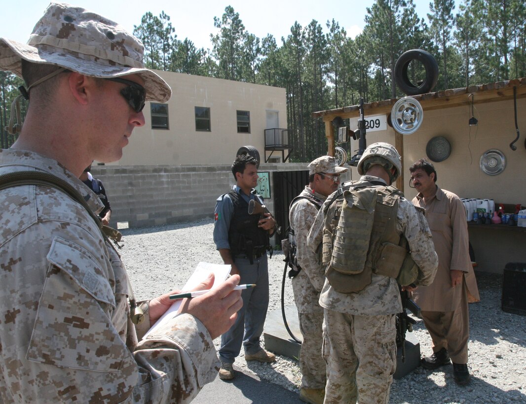 Lance Cpl. Randall Hernandez, squad leader for 2nd squad, 3rd platoon, 2nd Battalion, 6th Marine Regiment, 2nd Marine Division, talks with role players by using an interpreter. Lt. Matt Tweed looks on and evaluates Hernandez as he tries to communicate with the actors. The role players act as Afghan National Police and local citizens in Afghanistan. During the exercise the Marines with the battalion practiced searching for simulated IED's and communicating with the local population.