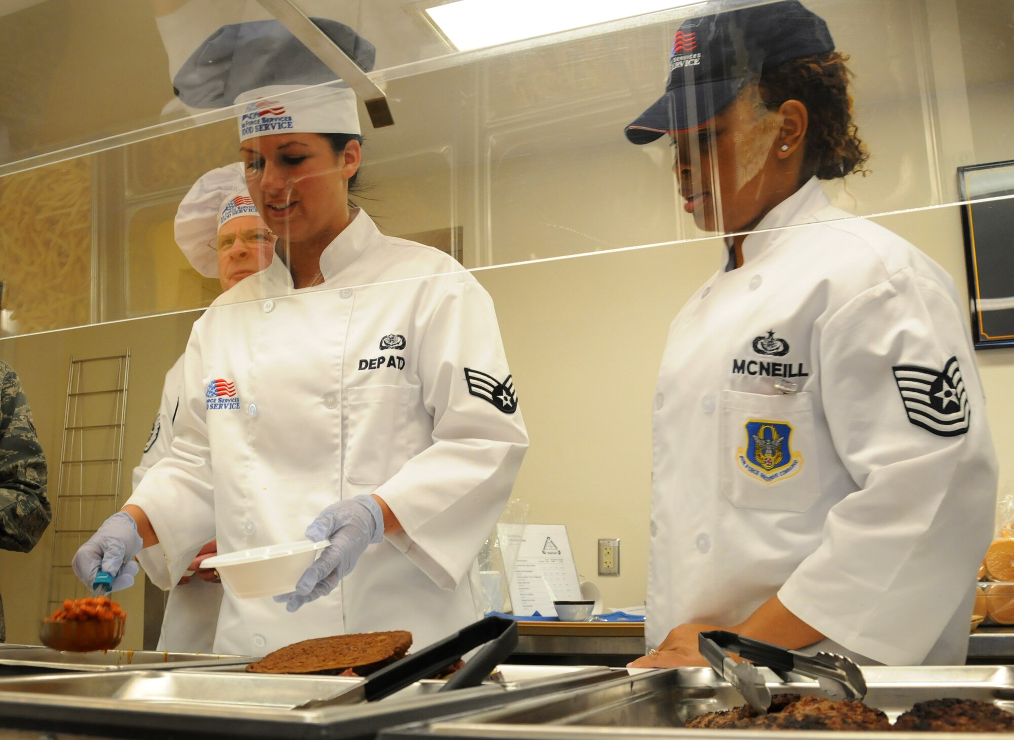Senior Airman Lauren K. Depatto, Force Support Squadron cook, demonstrates serving procedures to TSgt. Shakela T. McNeill, Hennessy inspector for Air Force Reserve Command, at the dining facility at the Minneapolis-St. Paul Air Reserve Station, Minn. (U.S. Air Force Photo/Tech Sgt. Bob Sommer)