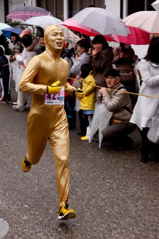 The “Million Dollar Marathoner,” a Japanese runner, sprints past spectators during the 6th annual Kintai Road Race near the Kintai Bridge Sunday. More than 2,200 running enthusiasts, including more than 30 Marines, sailors and station residents, competed in a unique cultural experience between two athletic cultures.