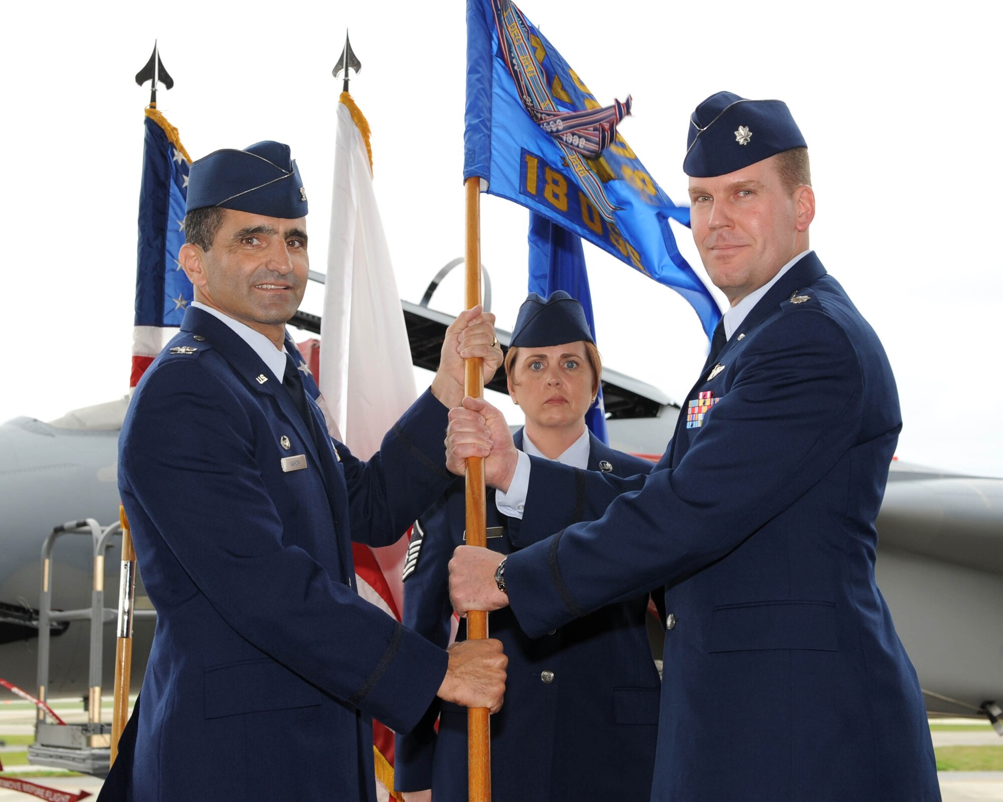 U.S. Air Force Col. David Nahom, 18th Operations Group commander, passes the squadron flag to Lt. Col. Robert Pekarek, the new 18th Operations Support Squadron commander, during the 18th OSS change of command ceremony on Kadena Air Base, Japan, March 2, 2012. The present-day ceremony is primarily symbolic; it represents the passing of authority from the outgoing commander to the incoming commander.
