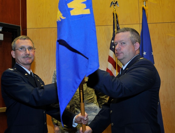 Col. Jack Wall, 151st Mission Support Group commander, passes the 151st Civil Engineer Squadron flag to unit’s incoming commander, Maj. Gene Buckner, during the change of command ceremony at the Utah Air National Guard Base in Salt lake City, Utah, 3 March, 2012. (U.S. Air Force Photo by Tech. Sgt. Jeremy Giacoletto-Stegall/Released)