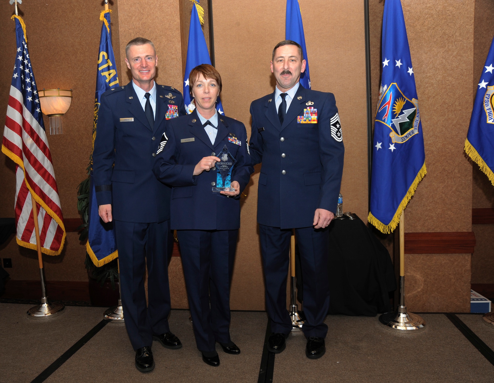 Oregon Air National Guard Commander Brig. General Steven Gregg (left) and Oregon State Air National Guard Command Chief Master Sgt. Mark Russell (far right) stand with Master Sgt. Melissa Adams who was selected overall Category III Airman of the Year of the 142nd Fighter Wing, Oregon Air National Guard, during the 18th Annual Oregon Air National Guard Awards Banquet, held on February 25, 2012 in Portland, Ore. (US Air Force Photograph by Tech. Sgt. John Hughel, 142nd Fighter Wing Public Affairs)(Released)