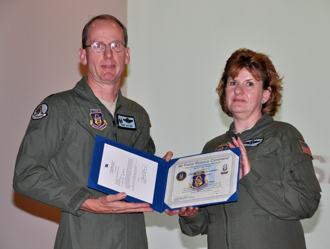 Senior Master Sgt. Kathy Lambert, 326th Airlift Squadron flight leader supervisor and loadmaster instructor, receives a certificate of recognition and patch from Lt. Col. David Arthur, 326th AS commander, March 3, 2012, at the theater, Dover Air Force Base, Del. She accumulated more than 10,000 hours of mishap-free flying during her Air Force Reserve career. (U.S. Air Force photo by Staff Sgt. Andria J. Allmond)