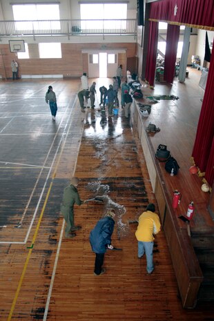 Marine Corps Air Station Iwakuni volunteers mop and squeegee the Minato Shogakko (Elementary School) gym floor here March 5. The gym acted as a shelter for locals in the aftermath of the earthquake and tsunami which struck this area of Japan March 11, 2011.