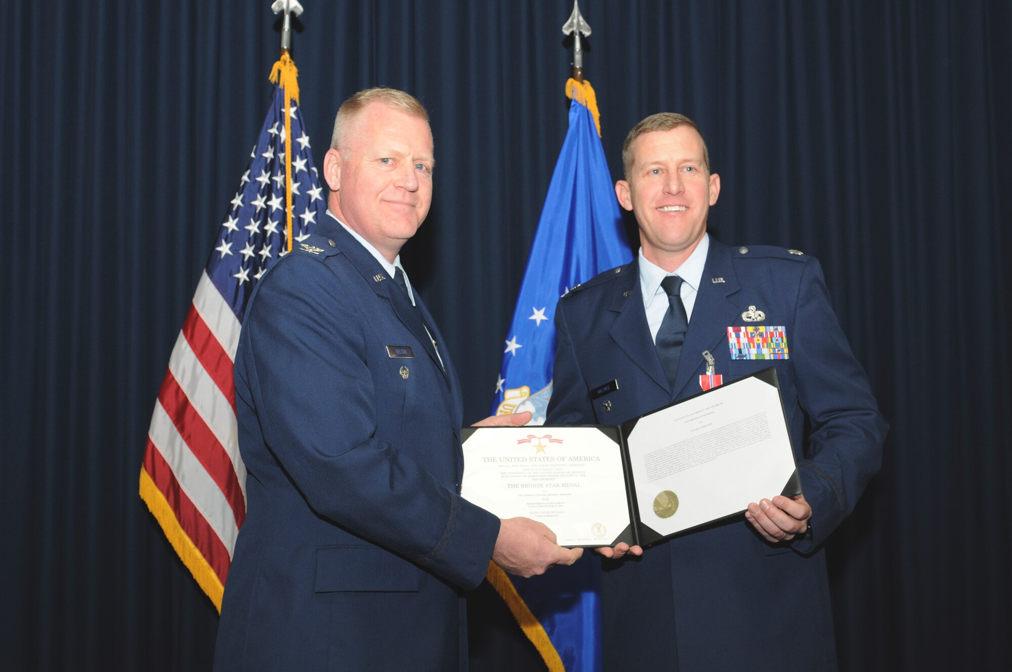 Col. Richard Nelson, Defense Logistics Agency Aviation, Richmond, Va., presents the Bronze Star Medal certificate to Lt. Col. Dave Wiesner, Air Force Safety Center conventional munitions branch chief, during a ceremony at Kirtland Air Force Base, March 2, for actions while deployed as 451st Expeditionary Maintenance Group deputy commander, Kandahar Airfield, Afghanistan. (U.S. Air Force photo/Keith Wright).