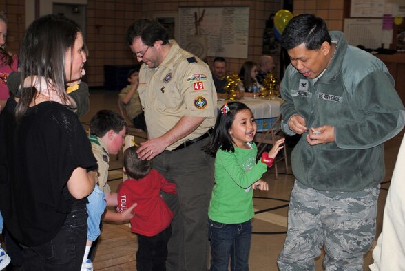 Col. H.B. Brual, 341st Missile Wing commander, along with the help of his daughter, Allison, unwrap commander's coins to be handed to the leaders of Cub Scout Pack 43 standing around him.  (U.S. Air Force photo/Airman 1st Class Cortney Paxton)