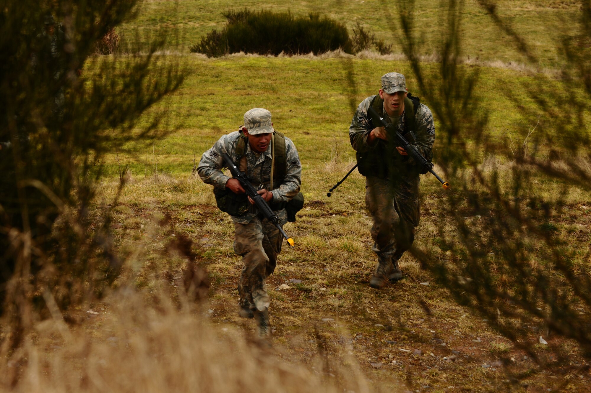 SPANGDAHLEM AIR BASE, Germany – Airman 1st Class Vicente Mattocks, left, 606th Air Control Squadron; and Senior Airman Coty Raphael, 52nd Medical Operations Squadron, advance on the enemy in a field next to Perimeter Road here during the patrolling training portion of the Ranger training course March 3. Any male Airman can volunteer for the annual training if they are serious about becoming a U.S. Army Ranger and their chain of command allows him to participate. The required three-day course prepares Airmen for what they will be tested on during the Ranger training school at U.S. Army Fort Benning, Ga. Out of the five Airmen enrolled in the training, Senior Airman Sean Reval, 52nd Security Forces Squadron, and Senior Airman Coty Raphael, 52nd Medical Operations Squadron, were the only participants to qualify to continue on to Ranger pre-assessment training at Sembach Air Base, Germany. (U.S. Air Force photo by Airman 1st Class Dillon Davis/Released)