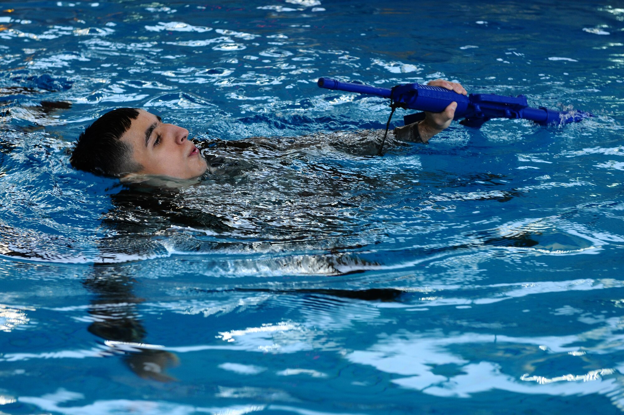 RAMSTEIN AIR BASE, Germany – Staff Sgt. Edgar Corona, 52nd Medical Operations Squadron, swims 15 meters while keeping his rifle above water during the water survival training portion of the Ranger training course inside the Ramstein Aquatic Center here March 2. The required three-day course prepares Airmen for what they will be tested on during the U.S. Army Ranger pre-assessment training course. The pre-assessment course includes water survival training, which takes place at Ramstein AB, as well as ruck marching and battle survival tactics that took place at Spangdahlem AB. Out of the five Airmen enrolled in the training, Senior Airman Sean Reval, 52nd Security Forces Squadron, and Senior Airman Coty Raphael, 52nd Medical Operations Squadron, were the only participants to qualify to continue on to Ranger pre-assessment training at Sembach Air Base, Germany. (U.S. Air Force photo by Airman 1st Class Dillon Davis/Released)