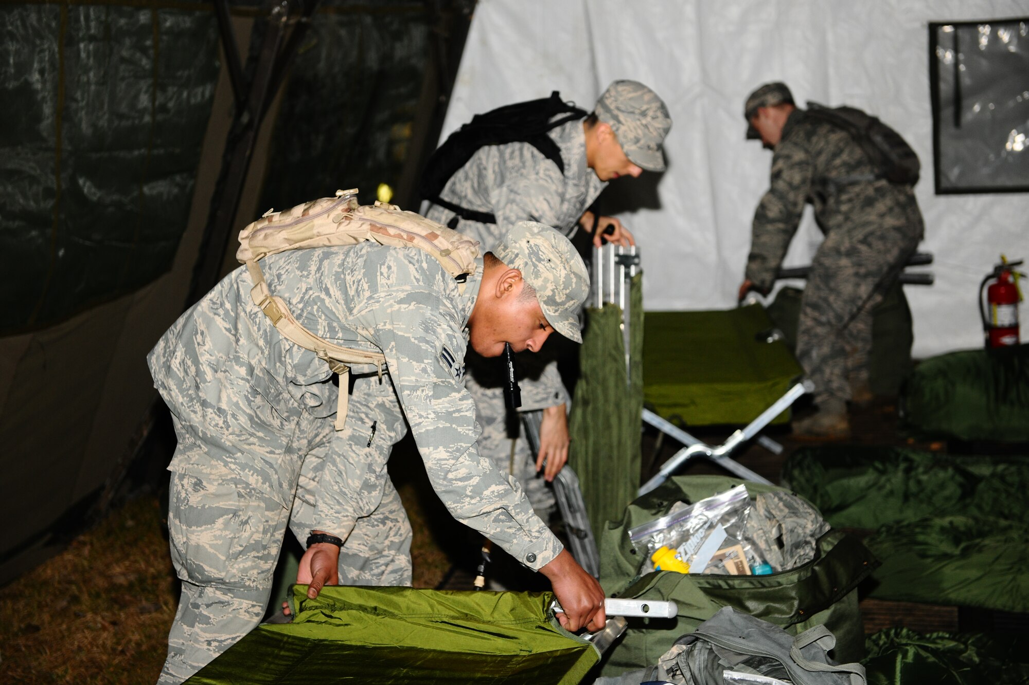 SPANGDAHLEM AIR BASE, Germany – Airman 1st Class Vicente Mattocks, left, 606th Air Control Squadro; Staff Sgt. Edgar Corona, center, 52nd Medical Operations Squadron; and Senior Airman Sean Reval, 52nd Security Forces Squadron, set up cots inside a Tent Extendable Modular Personnel tent during a Ranger training course here March 1. The required three-day course prepares Airmen for what they will be tested on during the U.S. Army Ranger pre-assessment training course. The pre-assessment course tests service members physically and mentally with challenges ranging from ruck marching to battle survival tactics. Out of the five Airmen enrolled in the training, Senior Airman Sean Reval, 52nd Security Forces Squadron, and Senior Airman Coty Raphael, 52nd Medical Operations Squadron, were the only participants to qualify to continue on to Ranger pre-assessment training at Sembach Air Base, Germany. (U.S. Air Force photo by Airman 1st Class Dillon Davis/Released)