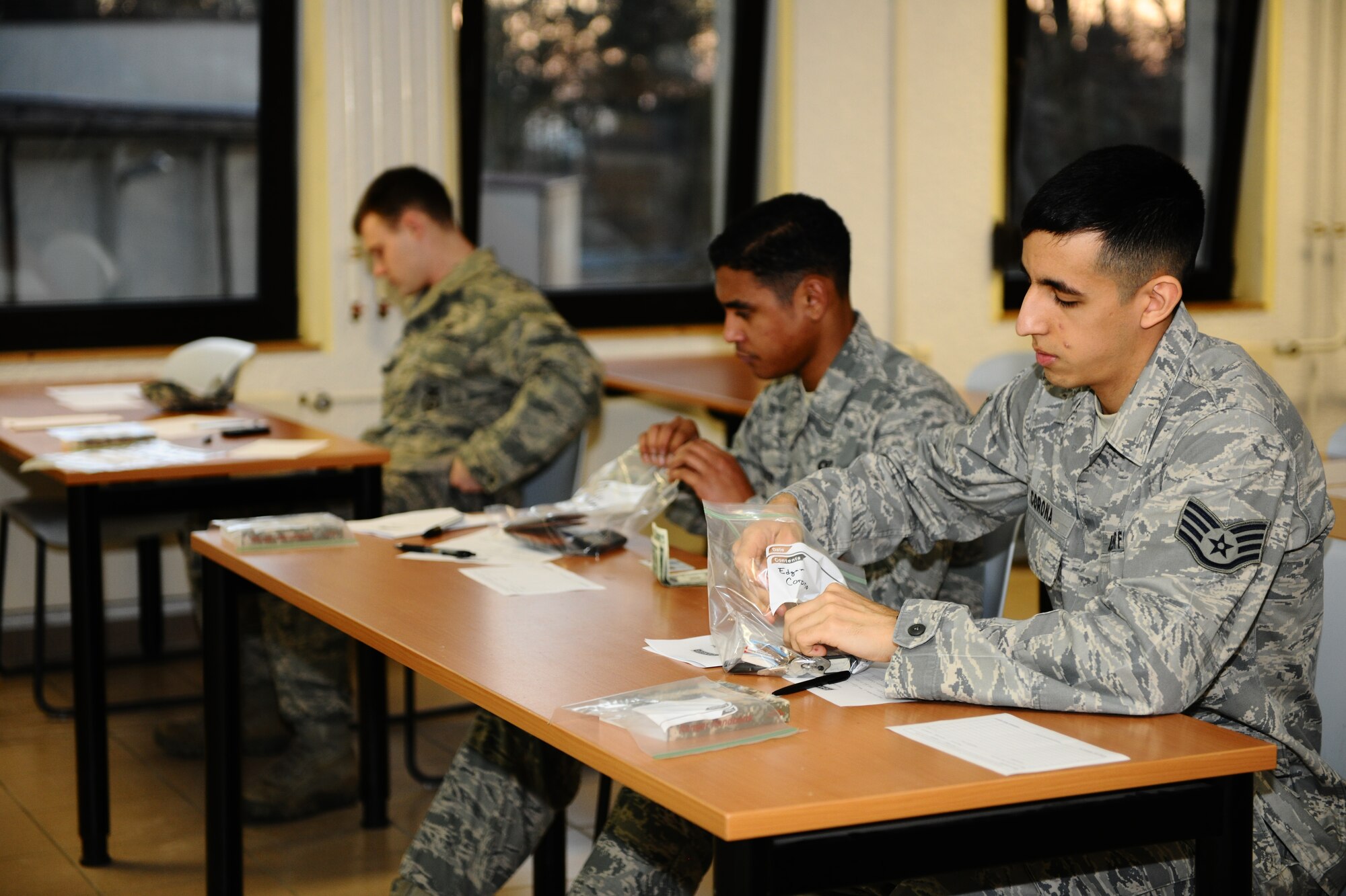 SPANGDAHLEM AIR BASE, Germany – Staff Sgt. Edgar Corona, right, 52nd Medical Operations Squadron; Airman 1st Class Vicente Mattocks, center, 606th Air Control Squadron; and Senior Airman Sean Reval, 52nd Security Forces Squadron, place their valuables in ziplock bags for safe keeping before the Ranger training course began inside Bldg. 603 here March 1. The required three-day course prepares Airmen for what they will be tested on during the U.S. Army Ranger pre-assessment training course. The pre-assessment course tests service members physically and mentally with challenges ranging from ruck marching to battle survival tactics. Out of the five Airmen enrolled in the training, Senior Airman Sean Reval, 52nd Security Forces Squadron, and Senior Airman Coty Raphael, 52nd Medical Operations Squadron, were the only participants to qualify to continue on to Ranger pre-assessment training at Sembach Air Base, Germany. (U.S. Air Force photo by Airman 1st Class Dillon Davis/Released)
