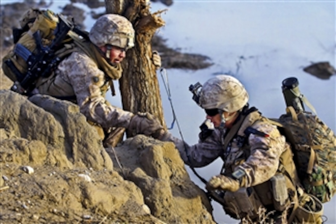 U.S. Navy Petty Officer 3rd Class Victor Castro (left) helps Marine Corps Lance Cpl. Josue Hernandez climb up a ravine during a partnered patrol with Afghan soldiers in Sagin in Afghanistan's Helmand province on Feb. 20, 2012.  Castro, a corpsman, and Hernandez, a rifleman, are assigned to India Company, 3rd Battalion, 7th Marine Regiment.  The Marines are training the Afghan soldiers to patrol on their own with the Marines in a support role.  