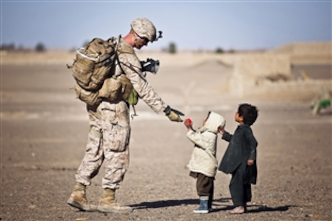 U.S. Marine Corps Lance Cpl. Tom Morton hands an Afghan child a toy during a security patrol in the Garmsir district of Afghanistan's Helmand province, Feb. 25, 2012. Morton is a team lead assigned to Kilo Company, 3rd Battalion, 3rd Marine Regiment. 