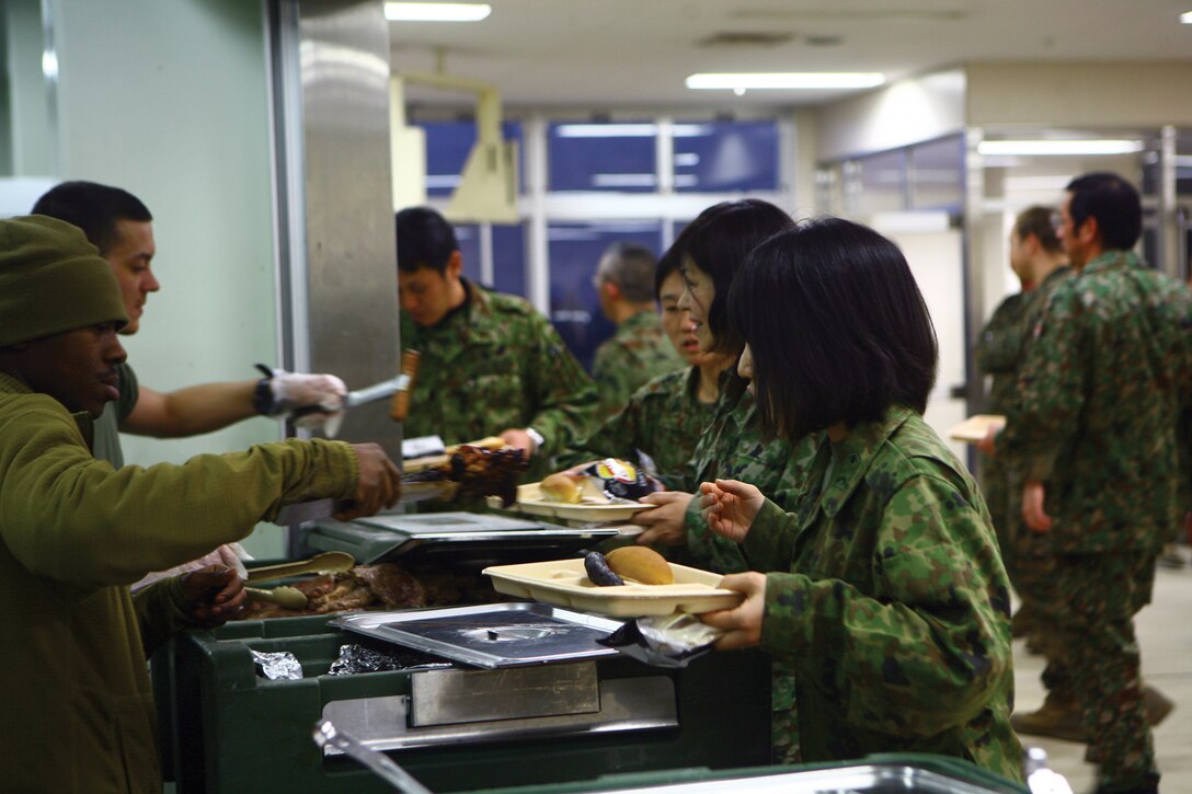 Members of the Japan Ground Self-Defense Force are served a warrior's meal at the Hijudai Maneuver Area, Oita Prefecture, Japan, Feb. 22. The meal was provided as a celebration for the successful completion of Artillery Relocation Training Program 11-4 by JGSDF members and the Marines of 3rd Battalion, 12th Marine Regiment, 3rd Marine Division, III Marine Expeditionary Force.