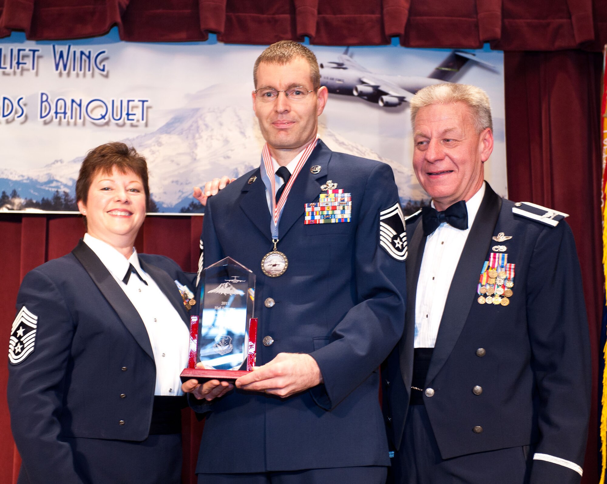 Senior Master Sgt. Mark Cherrix, 446th Maintenance Squadron, accepts his Civilian of the Year Supervisory award from Col. Bruce Bowers, 446th Airlift Wing Commander, and Command Chief Master Sgt. Gloria Bennett, at the Annual Awards Banquet at the McChord Club March 3. Cherrix is an air reserve technician and earned his award for the civilian part of his job. (U.S. Air Force photo by Master Sgt. Eliezer Yamzon)