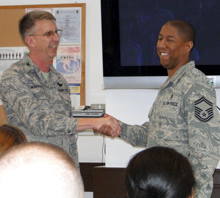 Col. Jeffrey Macrander, 920th Rescue Wing commander, Patrick Air Force Base, Fla., coins Senior Master Sgt. Anthony James, superintendent, 86th Contingency Aeromedical Squadron, Ramstein Air Base, Germany, during a visit to Germany with wing leadership to observe 920th deployed medical reservists in action. The leadership was impressed with the high level of care that the deployed 920th Aeromedical Staging Squadron members were consistently providing to wounded service members who came through their facility. (Courtesy photo)