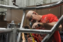 Paul Love, 902nd Mission Support Group Trainer Development Division, uses a portable grinder to smooth welds on a Barany chair cage on Joint Base San Antonio-Randolph March 5. JBSA-Randolph manufactures the Barany Chair for all of the Defense Department.(U.S. Air Force photo by Rich McFadden) 