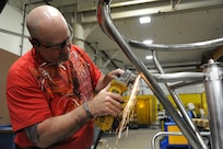 Paul Love, 902nd Mission Support Group Trainer Development Division, uses a portable grinder to smooth welds on a Barany Chair cage on Joint Base San Antonio-Randolph March 5. JBSA-Randolph manufactures the Barany Chair for all of the Defense Department.(U.S. Air Force photo by Rich McFadden) 
