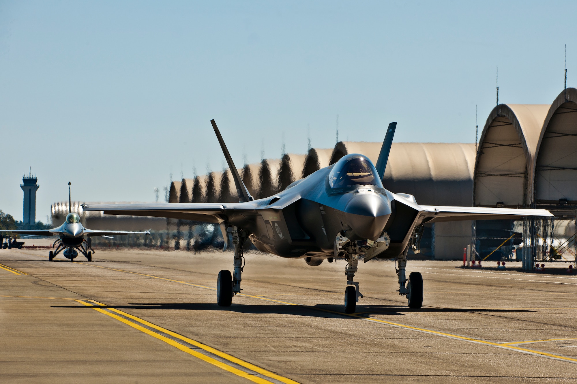 The F-35A Lightning II joint strike fighter taxis out for its first training sortie followed by an F-16 chase aircraft March 6 at Eglin Air Force Base, Fla.  (U.S. Air Force photo/Samuel King Jr.)