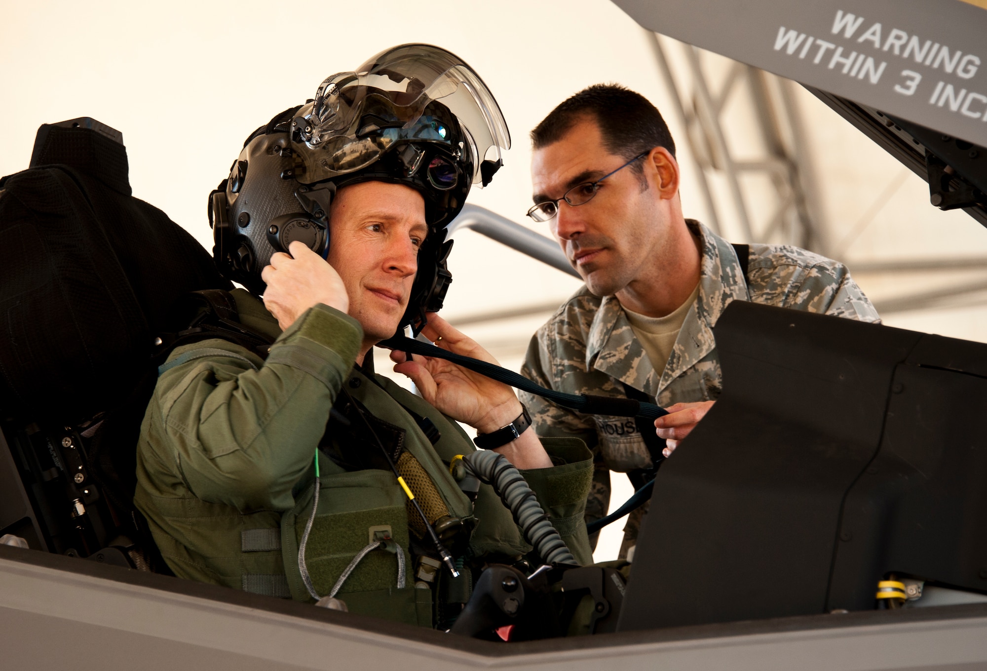 Lt. Col. Eric Smith, the 58th Fighter Squadron director of operations, puts on his helmet as Staff Sgt. Jeremy Houser, 33rd Aircraft Maintenance Squadron crew chief, assists prior to the first F-35A Lightning II joint strike fighter training sortie at Eglin Air Force Base, Fla., March. 6.  (U.S. Air Force photo/Samuel King Jr.)